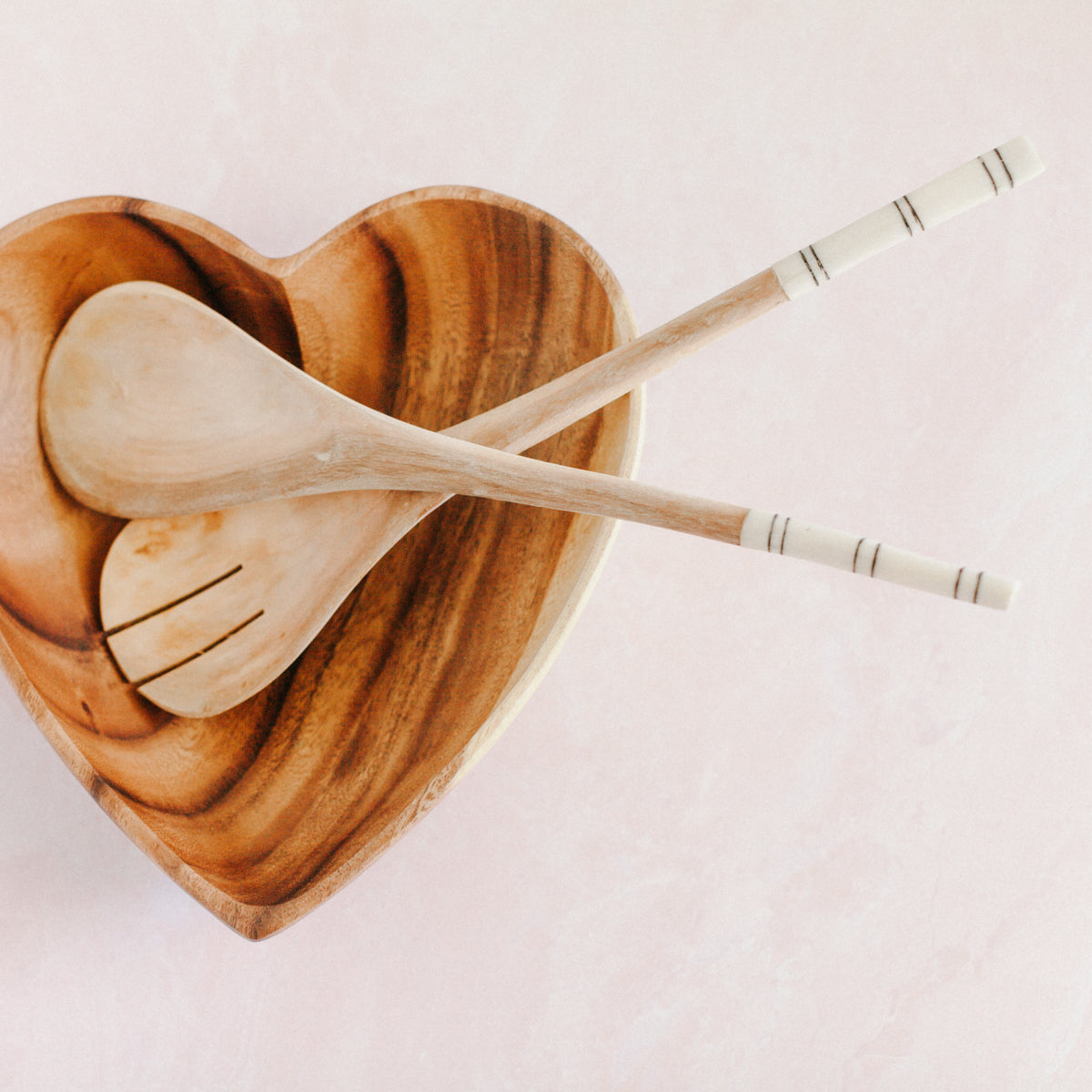 Close-up of handcrafted Kenyan striped salad servers showing striped cow bone handles and smooth olive wood spoons